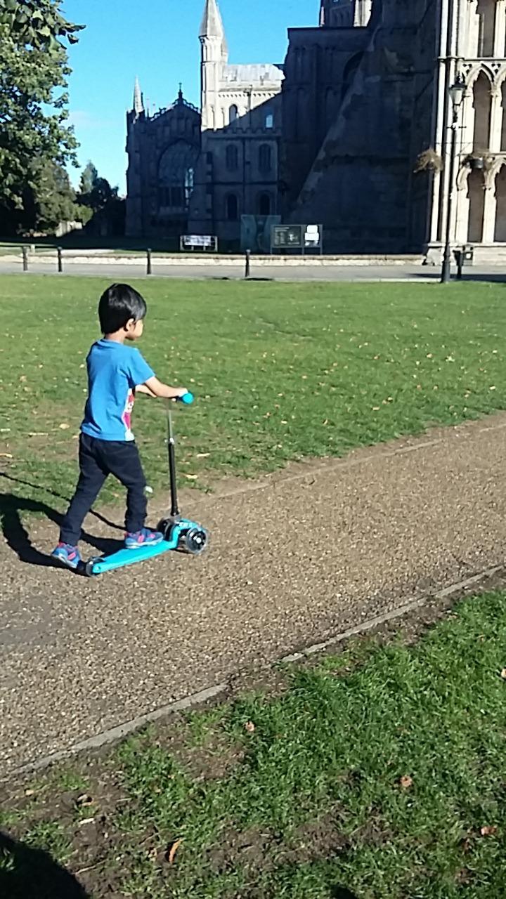 child scooting on a 3 wheel scooter in front of a castle