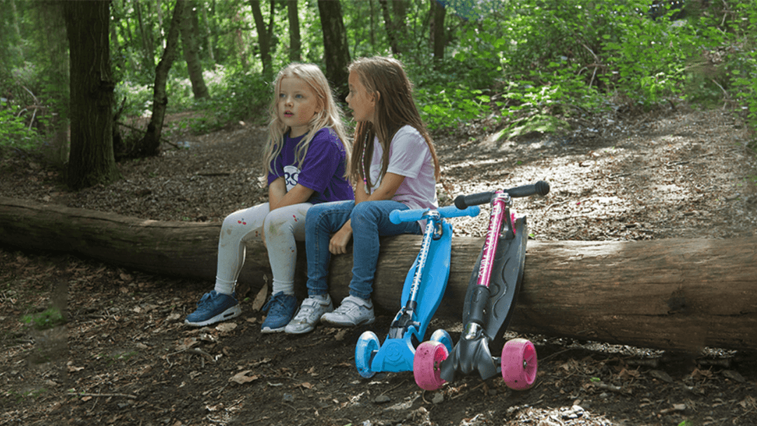 children sitting with their 3 wheel scooters